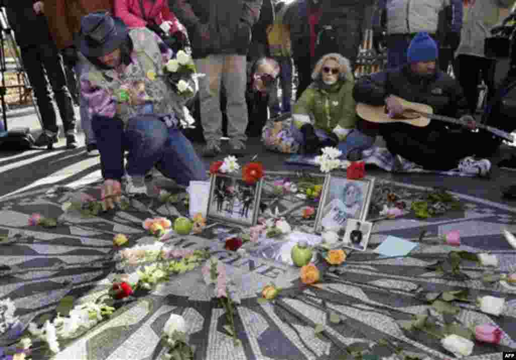 Gary Dos Santos, left, arranges flowers on the Imagine mosaic in the Strawberry Fields section of New York's Central Park, Wednesday, Dec. 8, 2010, the 30th anniversary of the death of John Lennon. (AP Photo/Richard Drew)
