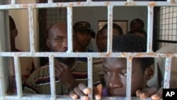FILE - African migrants look through bars of a locked door at Sabratha migrant detention center for men in Sabratha, Libya, October 2013.