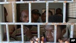 FILE - African migrants look through bars of a locked door at Sabratha migrant detention center for men in Sabratha, Libya, Oct. 2013.