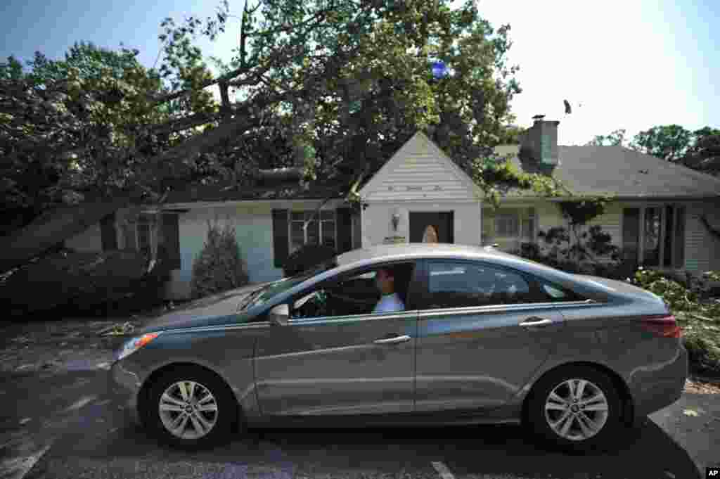 William Cosby (dari dalam mobilnya) melihat sebuah pohon besar yang tumbang menimpa rumahnya di Charleston, West Virginia (30/6). 