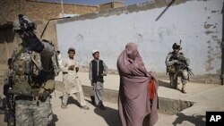 An Afghan woman walks among U.S. soldiers from on patrol in Kandahar City, Afghanistan, Oct. 22, 2010.