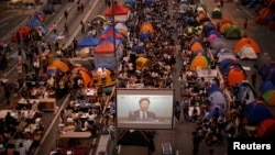 Pro-democracy protestors watch formal talks between student protest leaders and city officials on a video screen near the government headquarters in Hong Kong, Oct. 21, 2014. 