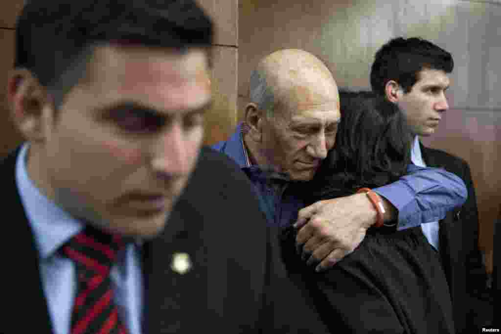 Former Israeli prime minister Ehud Olmert (2nd L) hugs a woman while waiting to hear his verdict at the Tel Aviv District Court, March 31, 2014.