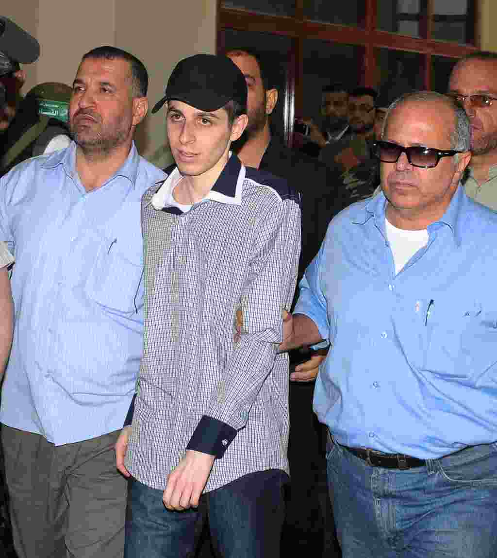 El soldado israelí, Gilad Shalit, acompañado por agentes de la inteligencia tras su arribo al área fronteriza de Rafah, en Egipto, el 18 de octubre de 2011.