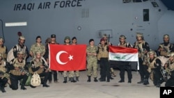 FILE - Turkish and Iraqi soldiers hold their national flags after the arrival of Iraqis in Silopi, near the Habur border gate with Iraq, southeastern Turkey, Sept. 25, 2017. 