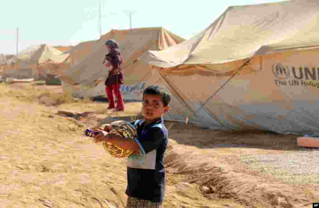 Một b&eacute; trai Syria trong trại tị nạn Zaatari ở Mafraq, Jordan, &nbsp;&ocirc;m g&oacute;i đồ chơi, quần &aacute;o, v&agrave; tiền, tặng cho trẻ em Hồi gi&aacute;o v&agrave;o ng&agrave;y đầu ti&ecirc;n lễ Eid al-Fitr của người Hồi gi&aacute;o, 19/8/12