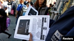 FILE - A New York City Health department official hands out information on the Ebola virus outside a school near a Bronx New York apartment building, Oct. 27, 2014.