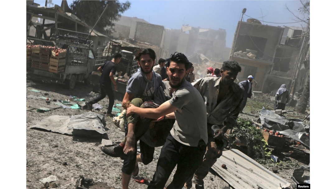 FILE - Men transport a casualty after what activists said were airstrikes by forces loyal to Syria's President Bashar al-Assad on a busy marketplace in Douma, near Damascus, Syria, Aug. 12, 2015.