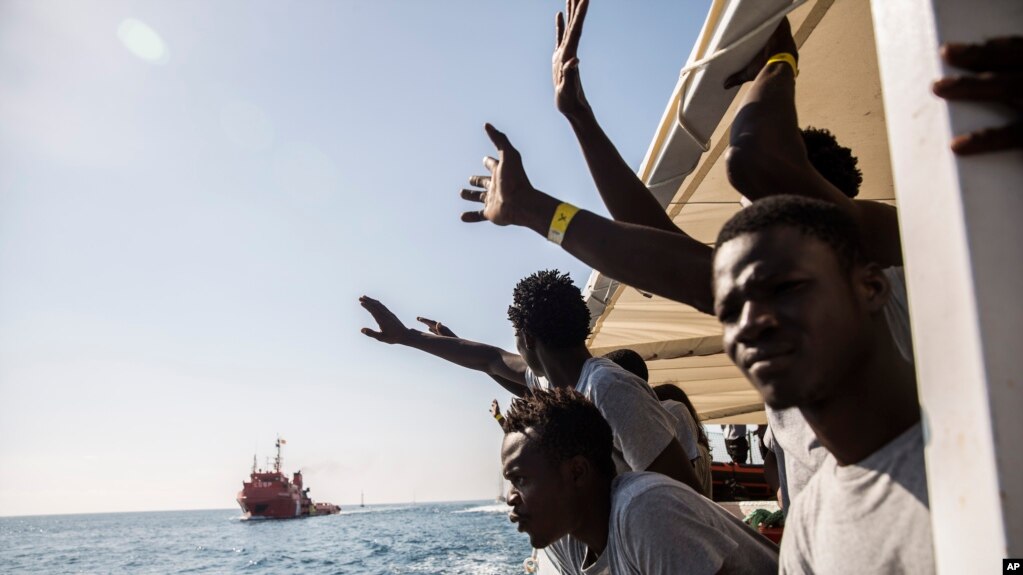 FILE - Migrants aboard the Open Arms aid boat, of Proactiva Open Arms Spanish NGO, react as the ship approaches the port of Barcelona, Spain, July 4, 2018. 