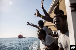 FILE - Migrants aboard the Open Arms aid boat, of Proactiva Open Arms Spanish NGO, react as the ship approaches the port of Barcelona, Spain, July 4, 2018.