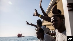 FILE - Migrants aboard the Open Arms aid boat, of Proactiva Open Arms Spanish NGO, react as the ship approaches the port of Barcelona, Spain, July 4, 2018. 