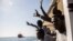 FILE - Migrants aboard the Open Arms aid boat, of Proactiva Open Arms Spanish NGO, react as the ship approaches the port of Barcelona, Spain, July 4, 2018. 