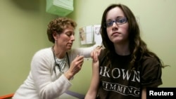 Nancy Brajtbord, RN, (kiri) sedang menyuntikkan vaksin Human Papillomavirus (HPV) kepada seorang remaja, di Dallas, Texas, 6 Maret 2018.