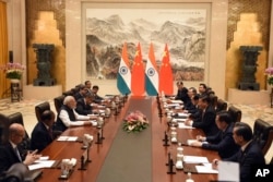 FILE - In this photo released by the Indian Ministry of External Affairs, Indian Prime Minister Narendra Modi, center left, and Chinese President Xi Jinping, center right, sit with delegation members for a meeting in Wuhan, China, Friday, April 27, 2018.