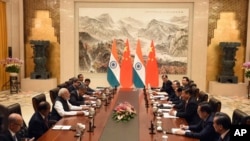 In this photo released by the Indian Ministry of External Affairs, Indian Prime Minister Narendra Modi, center left, and Chinese President Xi Jinping, center right, sit with delegation members for a meeting in Wuhan, China, April 27, 2018. 