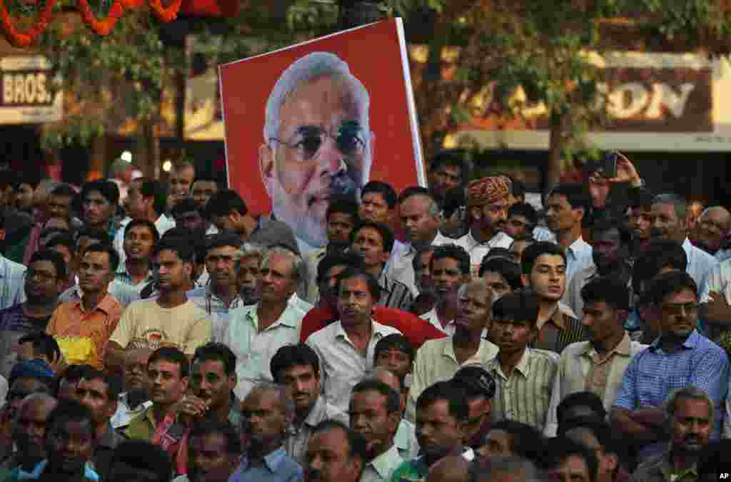 Warga India berkumpul untuk menonton upacara pengambilan sumpah perdana menteri baru mereka Narendra Modi dari layar televisi besar di sebuah pojokan jalan di New Delhi (26/5). (AP/Saurabh Das)