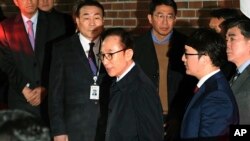 Former South Korean President Lee Myung-bak, centre, gets into a car as he is transferred to a detention centre, at his residence in Seoul early Friday March 23, 2018.