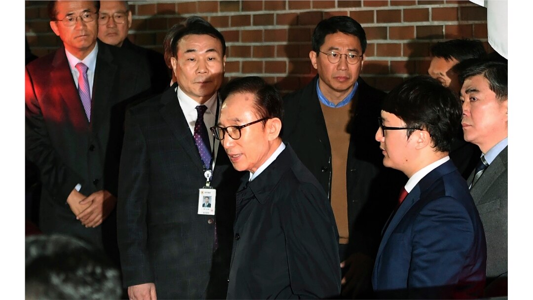Mantan Presiden Korea Selatan Lee Myung-bak, tengah, masuk ke dalam mobil saat ia dipindahkan ke pusat penahanan, di kediamannya di Seoul pada Jumat pagi, 23 Maret 2018. (Foto: AP)