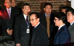 Mantan Presiden Korea Selatan Lee Myung-bak, tengah, masuk ke dalam mobil saat ia dipindahkan ke pusat penahanan, di kediamannya di Seoul pada Jumat pagi, 23 Maret 2018. (Foto: AP)
