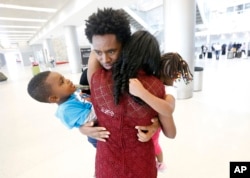 Olympic silver medalist Feyisa Lilesa, rear, of Ethiopia, hugs his wife Iftu Mulia, his daughter Soko, right, 5, and son Sora, left, 3, while picking up his family at Miami International Airport, Feb. 14, 2017.