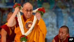 Pemimpin spiritual Tibet Dalai Lama membuka kalung bunga hadiah ulang tahunnya yang ke-78 di biara Buddha TIbet di Bylakuppe, sekitar 220 kilometer dari Bangalore, India, Juli 2013. 