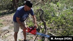 Johnny Gonzalez saws through a downed tree in Panama City, Fla., some of the destruction left by Hurricane Michael.