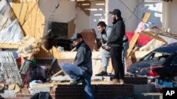 Jose Rivas, left, looks at tornado damage, Dec. 14, 2021, in Bowling Green, Ky.