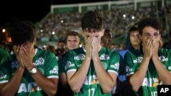 Chapecoense soccer players who did not travel with their team on a flight to Colombia that crashed, mourn during a tribute to the crash victims at Arena Condado stadium in Chapeco, Brazil, Nov. 30, 2016.