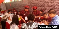 Petugas TPS berpakaian tradisional Tionghoa melayani warga yang hendak memilih (Foto: VOA/Petrus Riski).