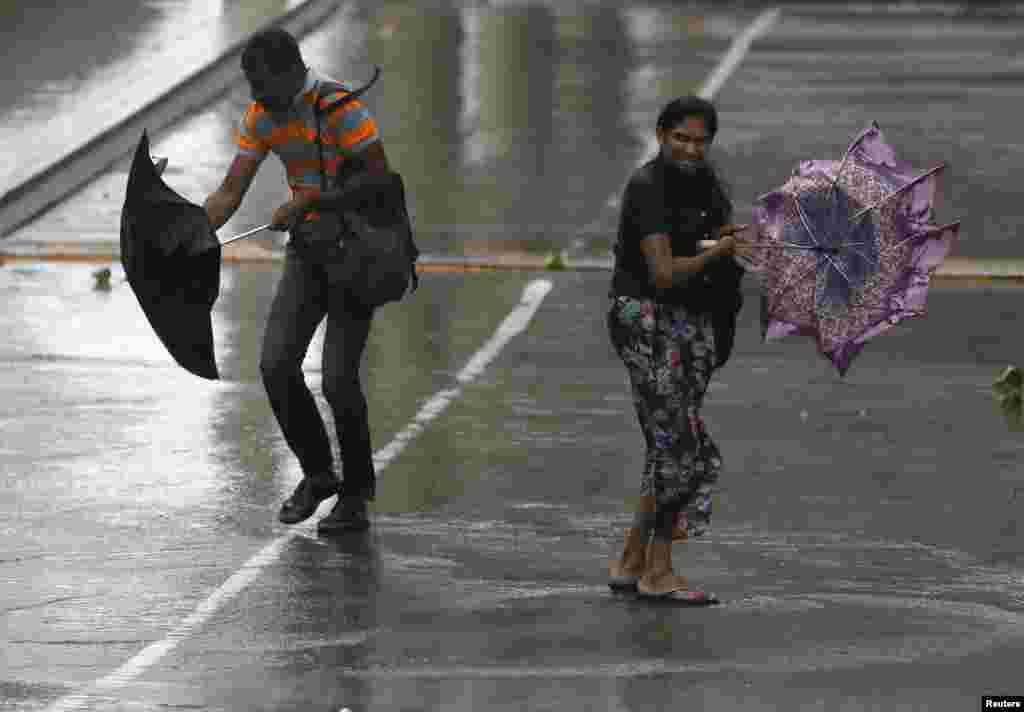 Seorang pria dan seorang wanita berjuang untuk mempertahankan payungnya dari hembusan angin yang kencang dan hujan di Kolombo, Sri Lanka.