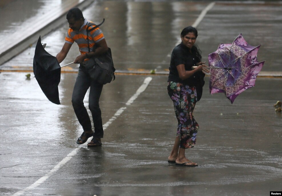 A man and a woman struggle to hold their umbrellas due to high wind and rain in Colombo, Sri Lanka.