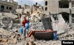 A Palestinian man carries his belongings from his destroyed house in Beit Hanoun town, which witnesses said was heavily hit by Israeli shelling and air strikes during Israeli offensive, in the northern Gaza Strip, July 26, 2014.