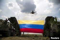 FILE - A Russian-made Sukhoi Su-30MKV fighter jet of the Venezuelan Air Force flies over a Venezuelan flag tied to missile launchers, during the "Escudo Soberano 2015" (Sovereign Shield 2015) military exercise in San Carlos del Meta in the state of Apure, April 15, 2015.