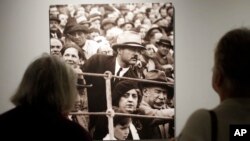 Museum visitors examine a 1927 photograph that shows Ernest Hemingway, center, at a bullfight in Pamplona Spain in the exhibit: "Ernest Hemingway: Between Two Wars" at the John F. Kennedy Presidential Library and Museum in Boston, April 12, 2016.