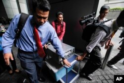 Cảnh sát Malaysia mặc thường phục mang một máy vi tính từ công ty 1MDB ra sau cuộc bố ráp ở Kuala Lumpur, Malaysia, ngày 8/7/2015.
