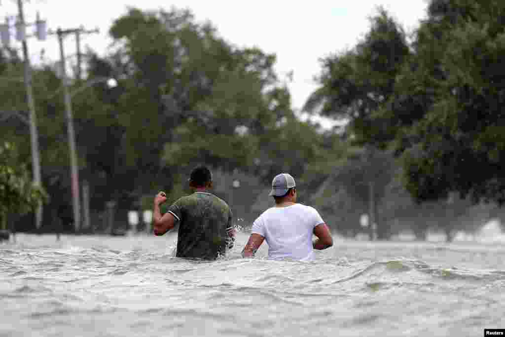 People wade through a flooded street after Hurricane Barry in Mandeville, Louisiana, July 13, 2019.