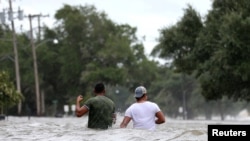 Orang-orang menyeberang jalan yang dilanda banjir yang dipicu oleh Badai Barry di Mandeville, Louisiana, AS, 13 Juli 2019. (Foto: dok).