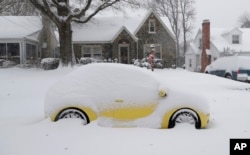 A snow-covered car is parked outside a home in Greensboro, North Carolina, Dec. 9, 2018. A massive storm brought snow, sleet, and freezing rain across a wide swath of the South on Sunday.