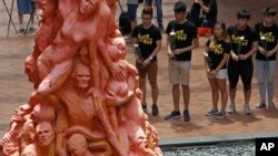 University students place flowers on the "Pillar of Shame" statue, a memorial for those injured and killed in the Tiananmen crackdown, at the University of Hong Kong, June 4, 2018.