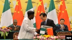 Le président Muhammadu Buhari du Nigeria, à gauche, et son homologue chinois Xi Jinping, à droite, se serrent la main lors d'une cérémonie de signature des accords au Grand Palais du Peuple, à Beijing, Chine, 12 avril 2016. epa/ Kenzaburō FUKUHARA / POOL