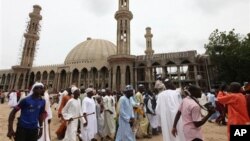 In this photo taken on Aug. 8, 2013, Nigerian Muslims walk past an uncompleted mosque in Maiduguri, Nigeria.