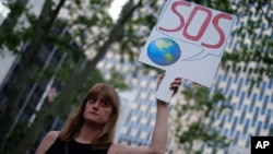 A woman displays a placard during a demonstration in New York on June 1, 2017, to protest U.S. President Donald Trump's decision to pull out of the 195-nation Paris climate accord deal. 