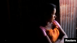 Bé gái mười bốn tuổi hành nghề mại dâm ngồi chờ khách tại một nhà chứa ở Faridpur, ở trung tâm Bangladesh.