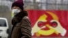 Arhiva - Čovek nosi masku ispred murala na kome je predstavljena modifikovan amblem vladajuće Komunističke partije Kine, tokom izbijanja epidemije koronavirusa, 28. januara 2020. (REUTERS/Aly Song)