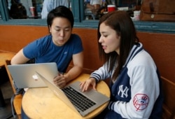 Colombian-born immigrant Nathaly Ordonez, right, studies her next semester's class options at the tuition-free, online University of the People, Thursday, Nov. 5, 2015, in New York, with Shota Hanawka, at left.
