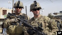 FILE - In this Feb. 5, 2012 file photo, U.S. soldiers part of the NATO- led International Security Assistace Force (ISAF) are seen alert at the scene of a suicide attack in Kandahar, south of Kabul, Afghanistan. The U.S. military is fully committed to its