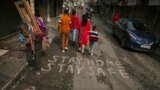 People walk past a message on a road during a weekend lockdown imposed to curb the spread of the coronavirus in Jammu, India, Jan. 23, 2022.