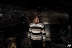 Mustafa Ismael Mustafa stands in his burned house as he returned home, March 29, 2017, after the neighborhood was retaken by Iraqi security forces during fighting with Islamic State militants, on the western side of Mosul, Iraq.