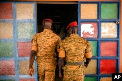 FILE - Two soldiers enter the Catholic church at the 10th RCAS army barracks in Kaya, Burkina Faso, April 10, 2021. The West African nation has been embroiled in unprecedented violence.