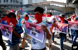 FILE - Masked members of the outlawed National Democratic Front of the Philippines, the umbrella organization of the communist movement, including the Communist Party of the Philippines, display placards while blocking traffic at a busy intersection in suburban Quezon city, northeast of Manila, Philippines, to urge peace talks as they celebrate its 45th anniversary, April 23, 2018.